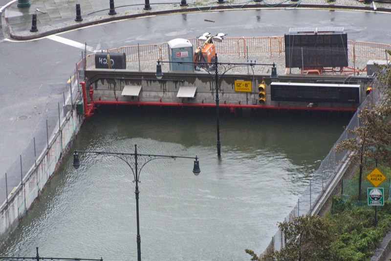 The entrance to the Battery Park Underpass filled with harbor water to just below its clearance sign, street lamps standing in the flood, the morning after Hurricane Sandy